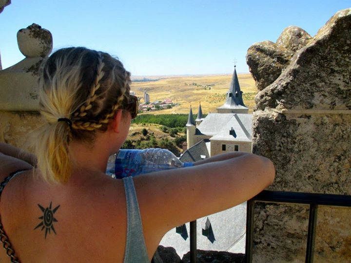 A woman with braids in her standing at the edge of a building looking off into the distance