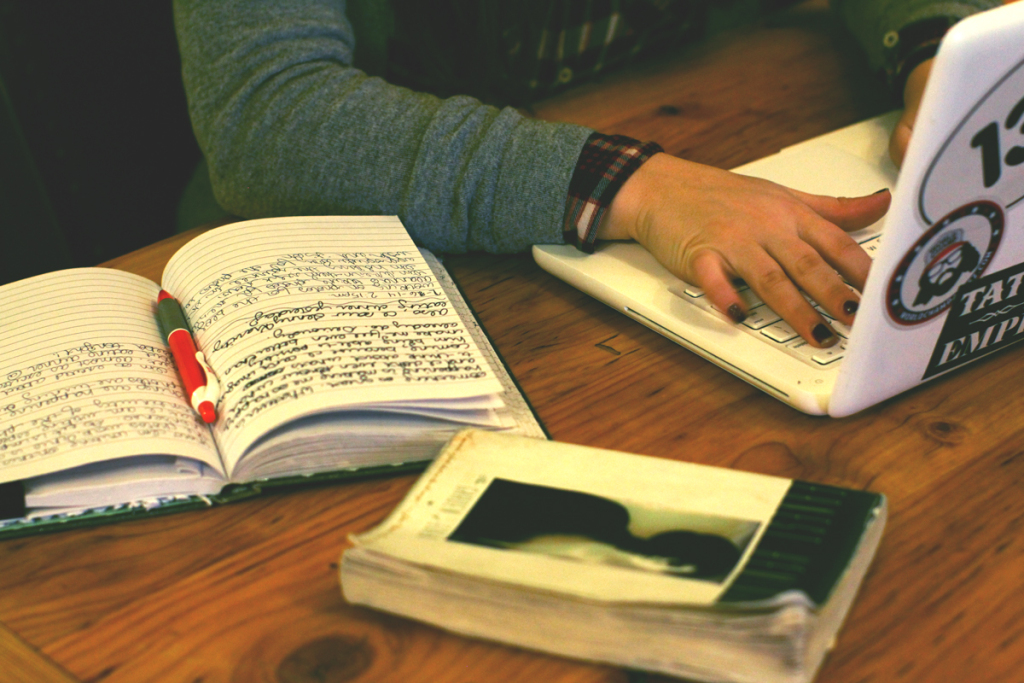 girl studying with books and macbook at a coffee shop